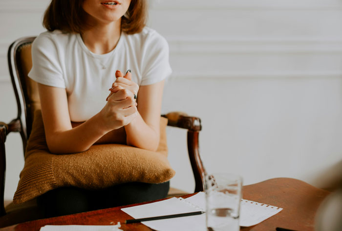 Woman sitting with folded hands, discussing sister who worked out and looks good at wedding, expressing frustration. Woman sitting with folded hands, discussing sister who worked out and looks good at wedding, expressing frustration.