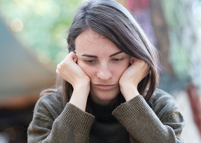 Woman looking sad and contemplative, struggling to ignore that husband has a mistress attempting to contact her.