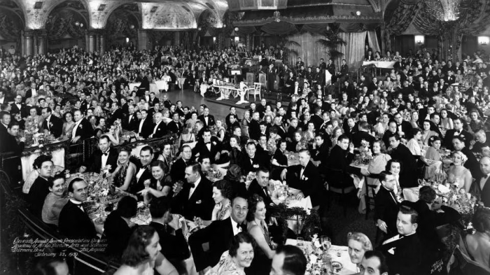 Large black and white photo of a formal dinner event showcasing the elite club atmosphere at an Oscar-winning gathering.