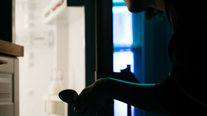 Person reaching into a fridge at night, illustrating common childhood habits many thought were unique to them.