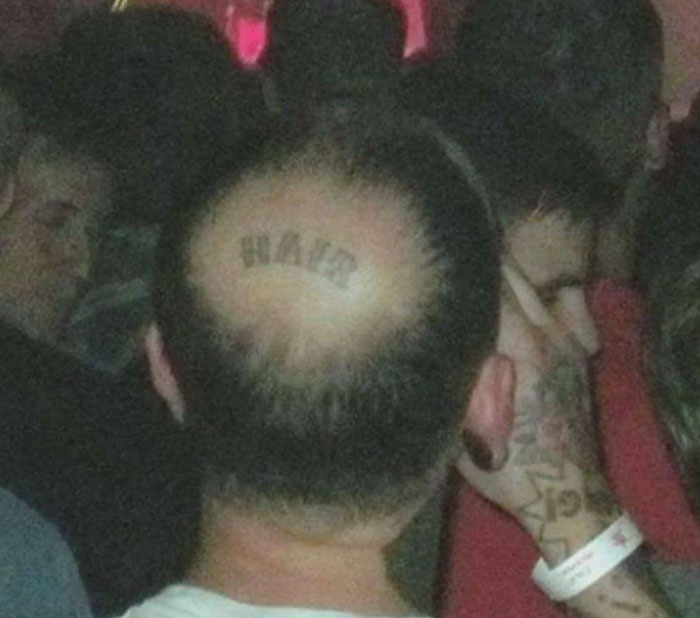 Man with a tattoo on his bald head that reads hair, one of many ink fails turning bad ideas into regrets.