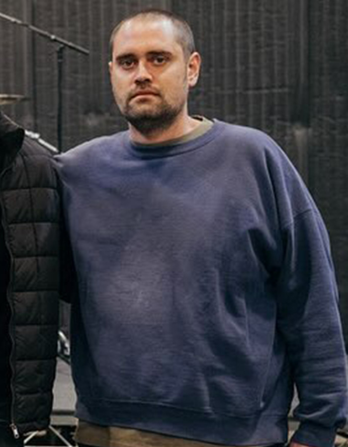 Man in a blue sweatshirt standing indoors, related to Nick Reiner&rsquo;s account raising disturbing talk and breaking point signs.