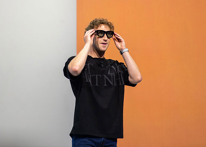 Man wearing smart glasses on stage, demonstrating augmented reality technology related to Meta workers' user experiences.