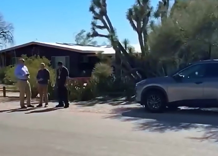 Three people standing near a house by a Phoenix canal, related to the body of woman found in Nancy Guthrie case.