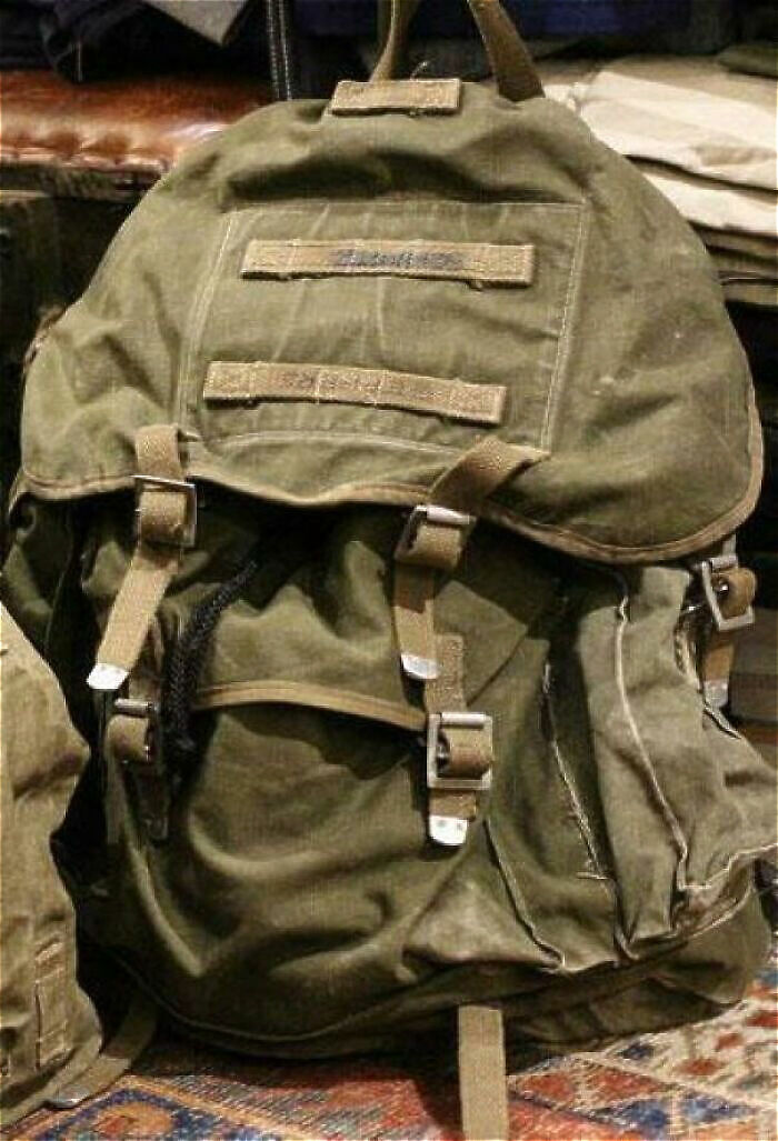 Old military-style backpack with buckles and straps found among bizarre and creepy things in old homes.