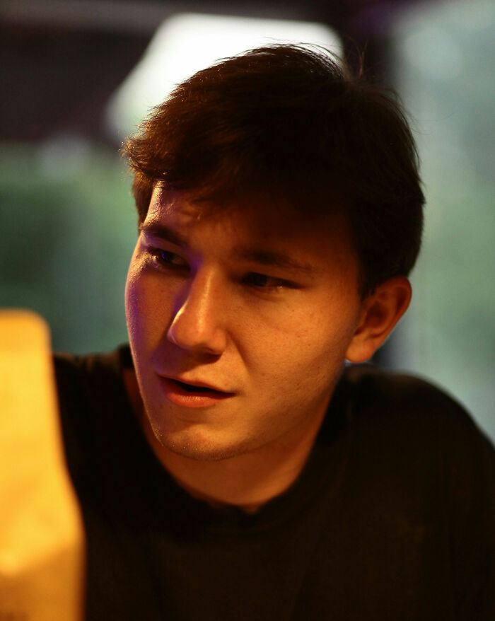 Young man indoors looking curious and puzzled, reflecting on weird and unhinged family traditions he probably doesn't have.