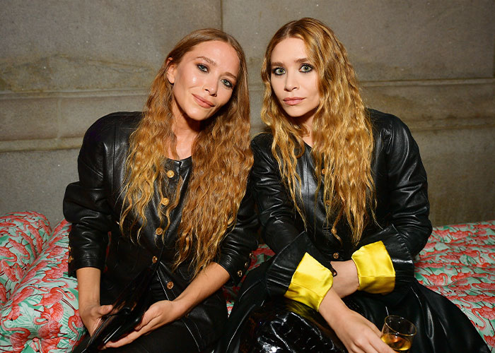 Mary-Kate and Ashley Olsen seated together, wearing black leather outfits, highlighting their surprising rift and disappearance.