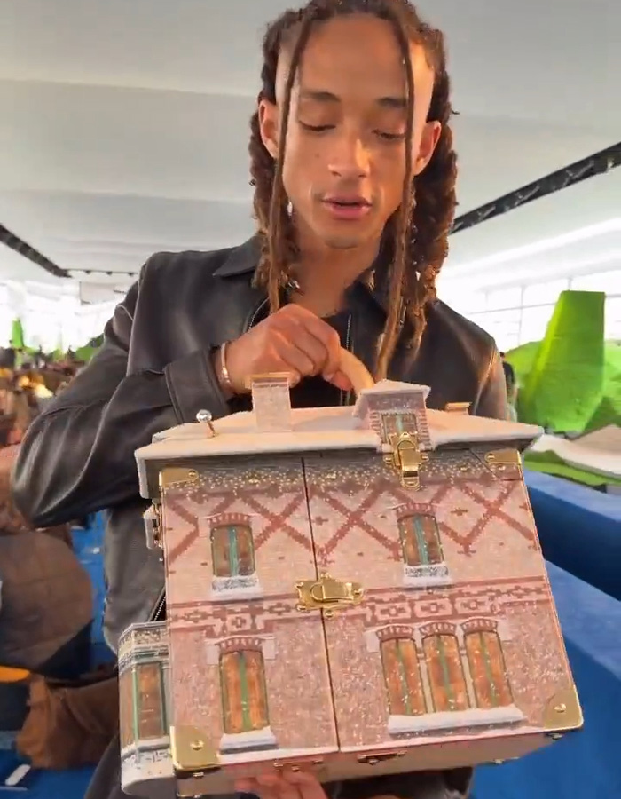 Jaden Smith holding a detailed house bag with a brick design while giving a tour of the unique accessory.