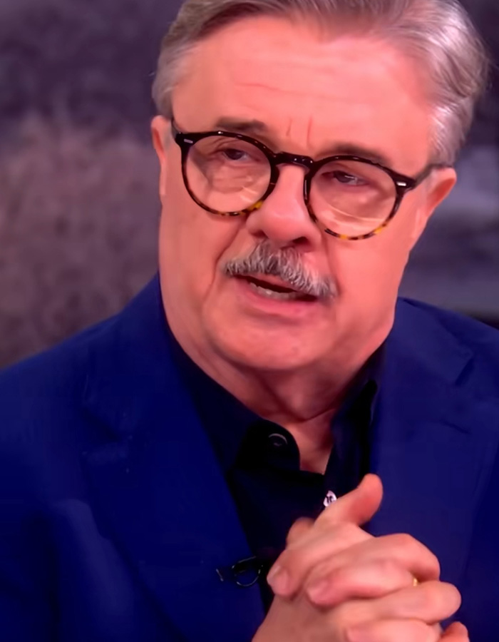 Older man with glasses in a navy jacket discussing Timoth&eacute;e Chalamet as a sage ahead of the Oscars in an interview setting.