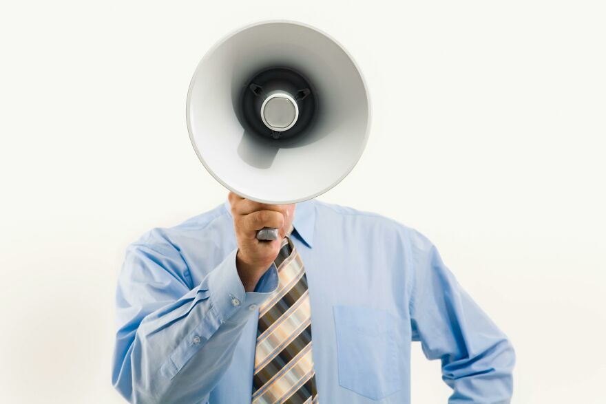 Man in blue shirt using a megaphone, illustrating practical psychology tricks in real-world communication situations.