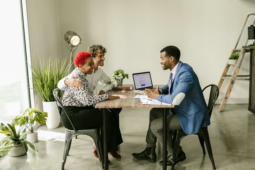 A diverse group having a friendly conversation at a table, illustrating small behaviors that make people like you more.
