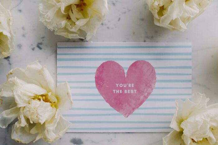 Pink heart with you're the best text on a striped card surrounded by white flowers, symbolizing beliefs and opinions challenge