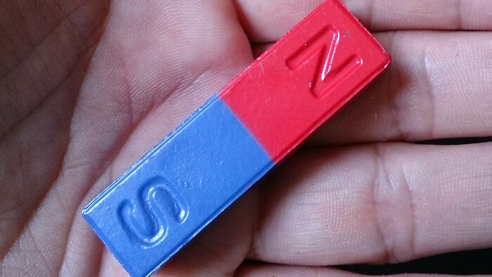 Close-up of a hand holding a red and blue magnet, a common childhood curiosity and unique kid experience.