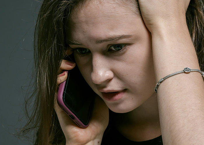 Jovem parecendo angustiada enquanto falava ao telefone, capturando um momento de revelação emocional em uma conversa sobre divórcio