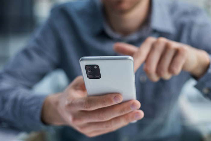 Person holding a smartphone, sharing a message about a tumour and experiencing the loss of a friend.