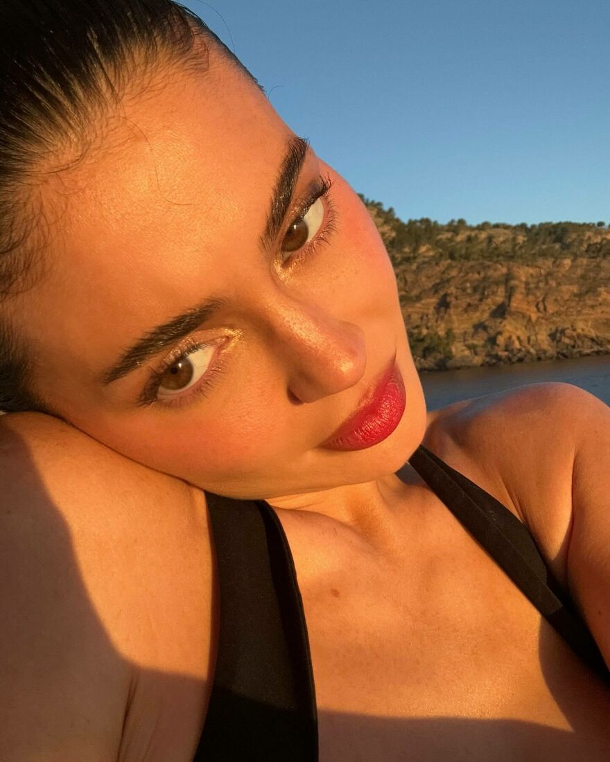 Close-up of Kylie Jenner showing her skin and makeup details, highlighting features before and after procedures outdoors.