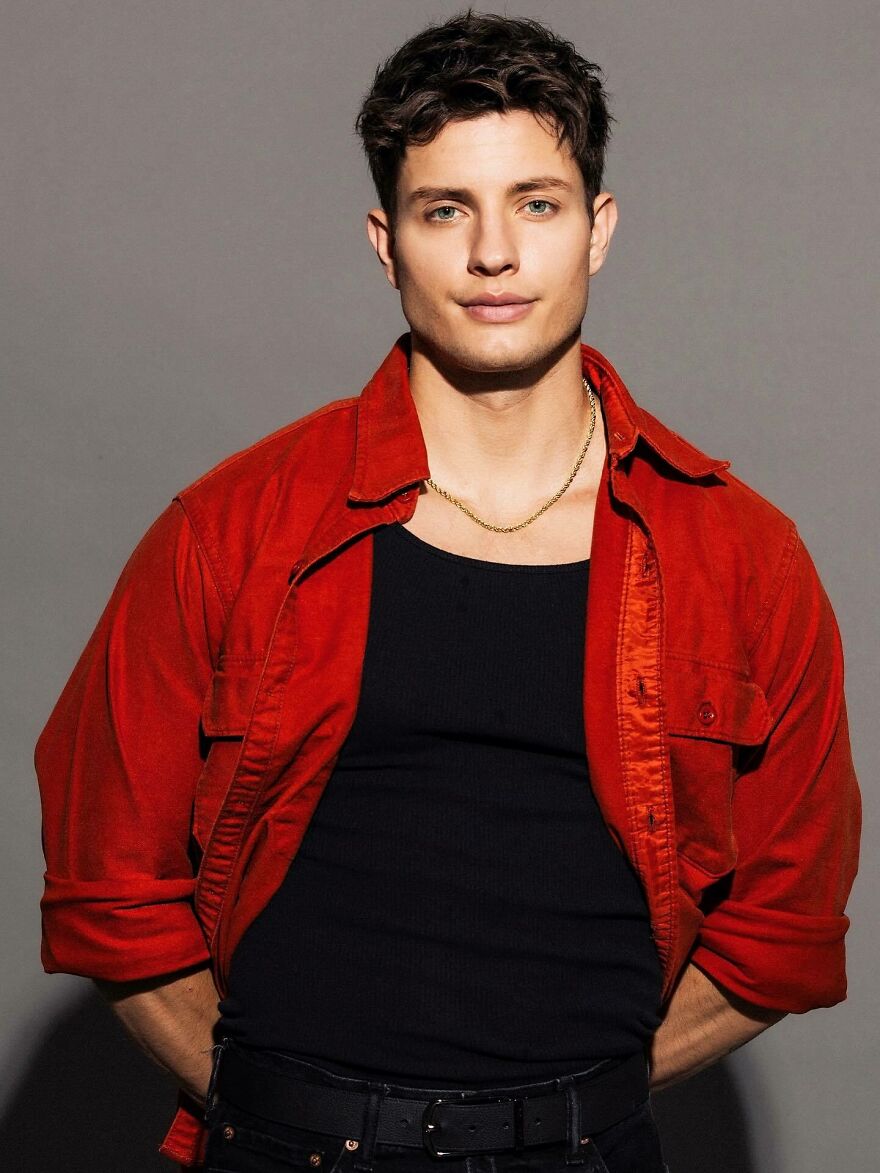 Matt Rife standing against gray background wearing red shirt and black tank top addressing plastic surgery rumors. Matt Rife standing against gray background wearing red shirt and black tank top addressing plastic surgery rumors.
