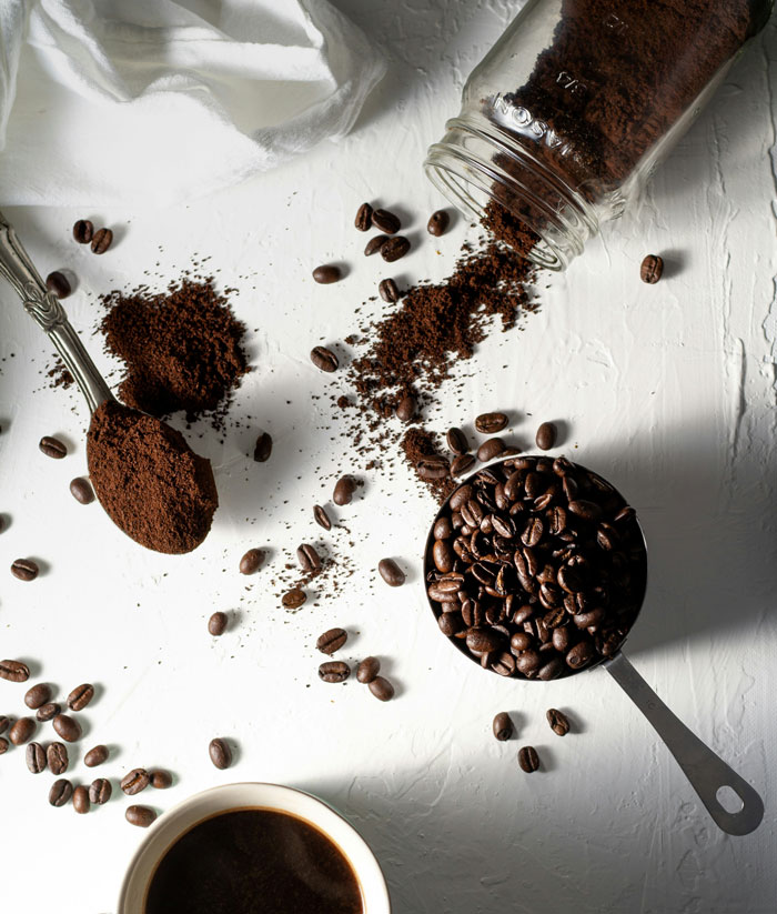 Coffee beans and grounds scattered on a white surface with a cup of black coffee, symbolizing neurological development in adulthood.