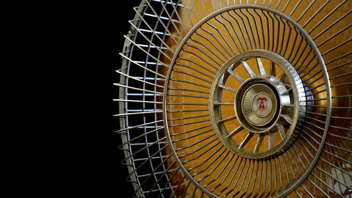 Close-up of a vintage fan grill with a yellowish blade, illustrating nostalgic childhood memories everyone thought were unique.