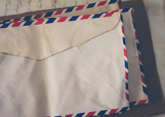 Old airmail envelopes stacked on a dark surface, evoking secrets and stories related to messy love triangle revelations.