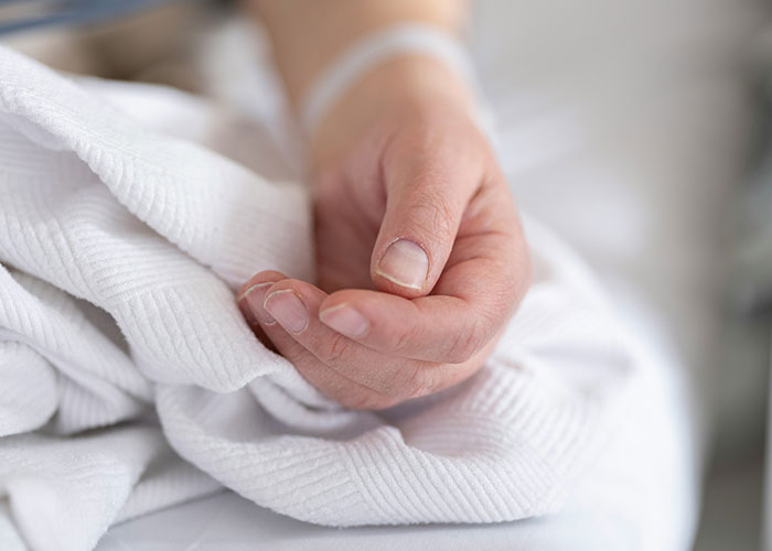 Close-up of a patient’s hand resting on a hospital bed, illustrating medical secrets and dark healthcare realities.