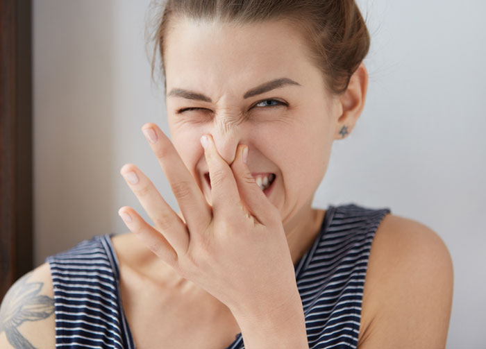 Young woman laughing and covering her nose, illustrating weird and adorable relationship moments women learn about men.