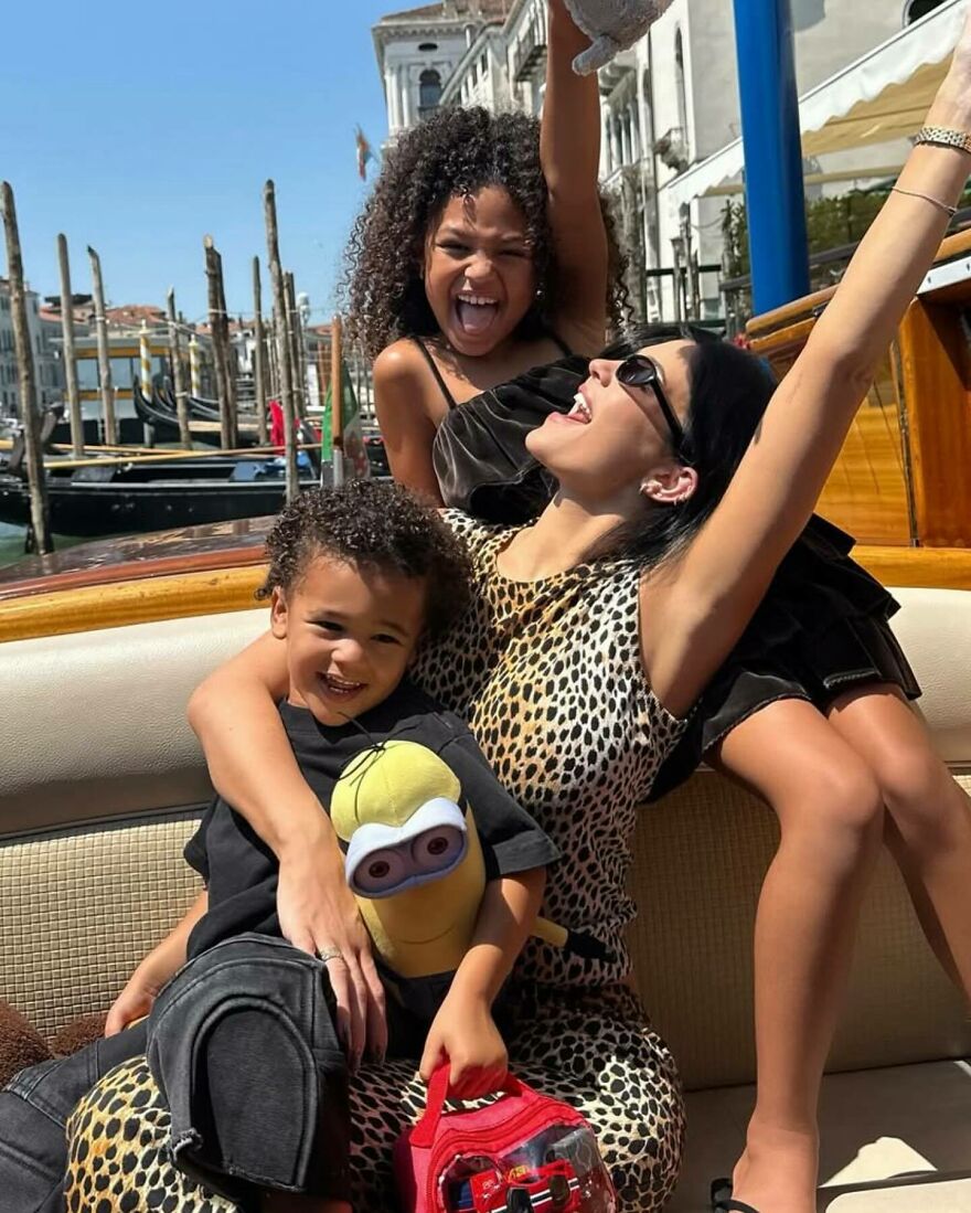Kylie Jenner up close with her children on a boat, enjoying a sunny day in a scenic waterfront location.