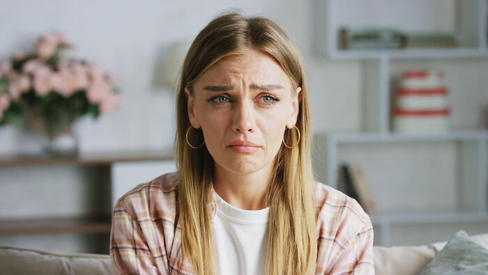 Sad woman sitting on a couch looking distressed, representing common struggles women thought were just part of being a woman.
