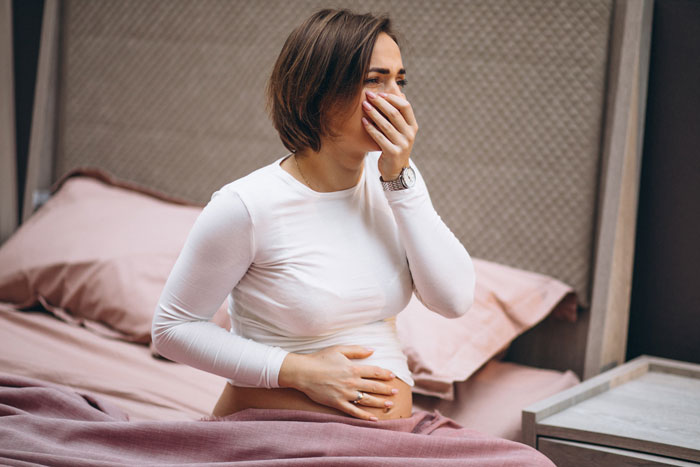 Jovem na cama segurando a barriga de grávida e cobrindo a boca, refletindo a preocupação com os resultados secretos dos testes de paternidade. Jovem na cama segurando a barriga de grávida e cobrindo a boca, refletindo a preocupação com os resultados secretos dos testes de paternidade.