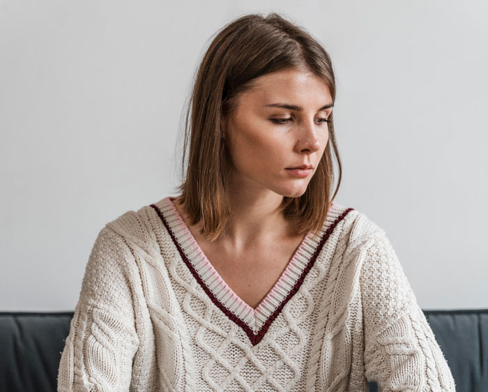 Young woman in a white sweater looking down, appearing worried and uneasy about her brother-in-law near her daughter. Young woman in a white sweater looking down, appearing worried and uneasy about her brother-in-law near her daughter.