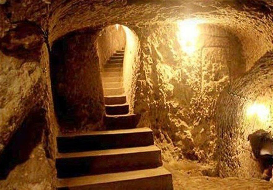 Dimly lit ancient underground city passage with stone walls and stairs, showcasing mysterious underground cities architecture.