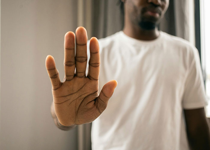 Man in white shirt holding up hand in stop gesture, symbolizing the moment an ex revealed their true self in divorce.