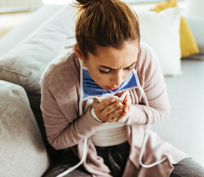 Woman sitting on couch looking frustrated, holding her hands near her mouth, illustrating dumb partner moments in relationships.