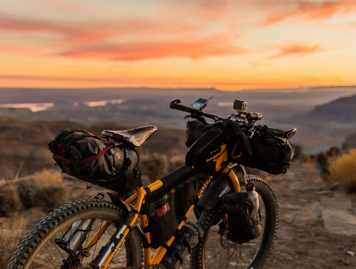 A fully loaded bikepacking bicycle on a trail at sunset, evoking the feeling of terrifying woods experiences.