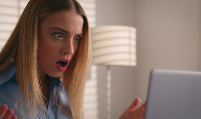 Woman looks shocked and confused while staring at laptop, illustrating coworker knowledge and therapist connection surprise.