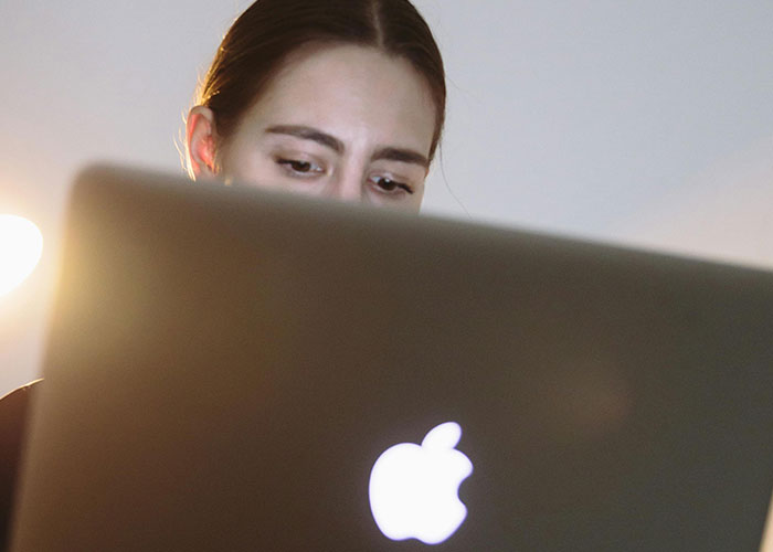 Young woman focused on her laptop screen, researching juicy chaotic secrets about messy love triangles online.