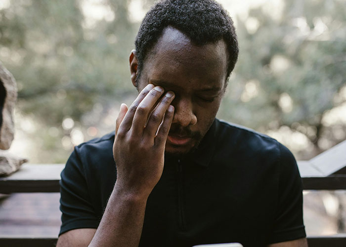 Man in black shirt rubbing his face, reflecting on a moment of emotional realization about a past relationship.