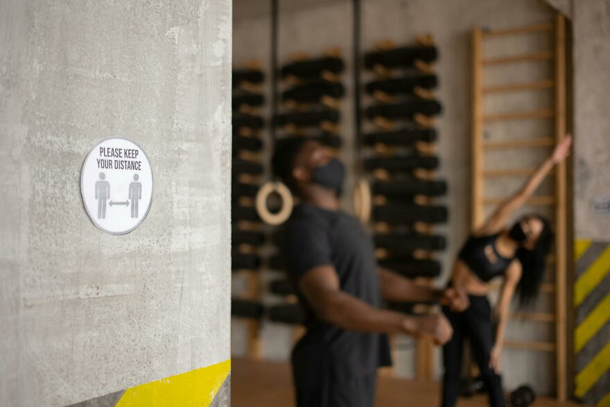 People practicing fitness in a gym with social distancing sign, illustrating practical psychology tricks in real-world situations.