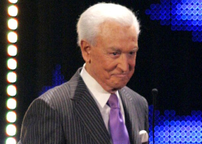 Older celebrity man in a pinstripe suit and purple tie at a lit event, illustrating encounters with celebrities who turned out to be jerks