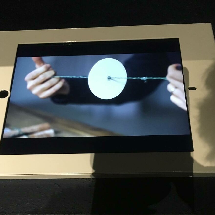 Hands holding a curious object with a string and circular component, highlighting the object's dazzling origins.