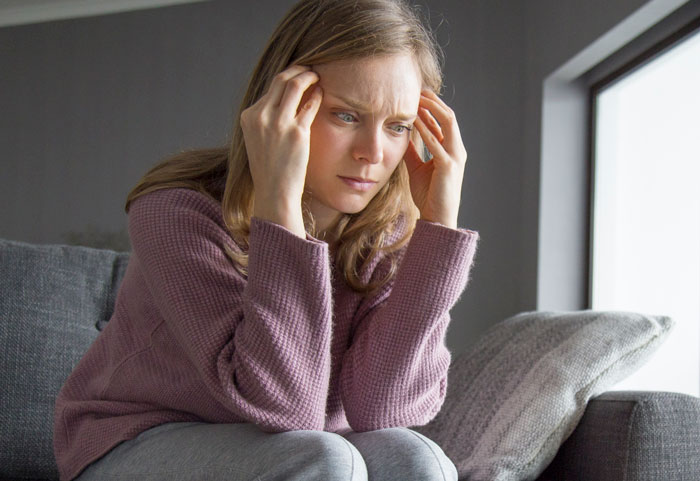 Woman looking confused and stressed at home, unsure how coworkers know personal details about her life.