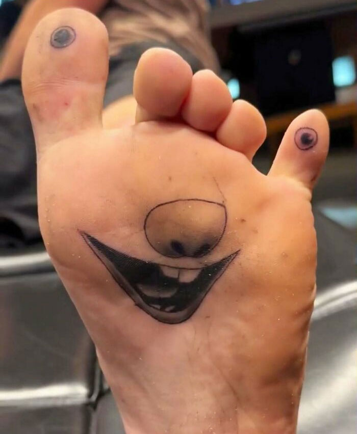Tattoo fail on foot with poorly done smiley face and unintended ink marks causing permanent regret example.