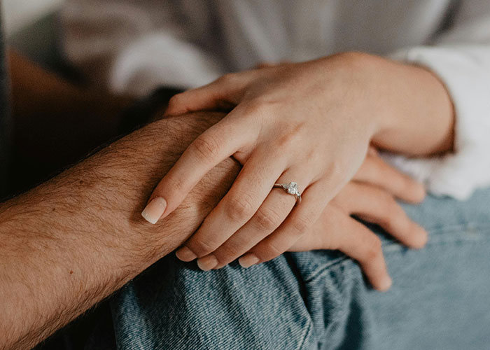 Close-up of two hands gently holding each other, symbolizing love and the complexity of a messy love triangle.