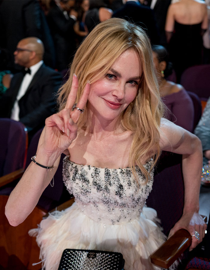 Nicole Kidman at the Oscars wearing a white embellished dress and flashing a peace sign, fans notice odd details in appearance.