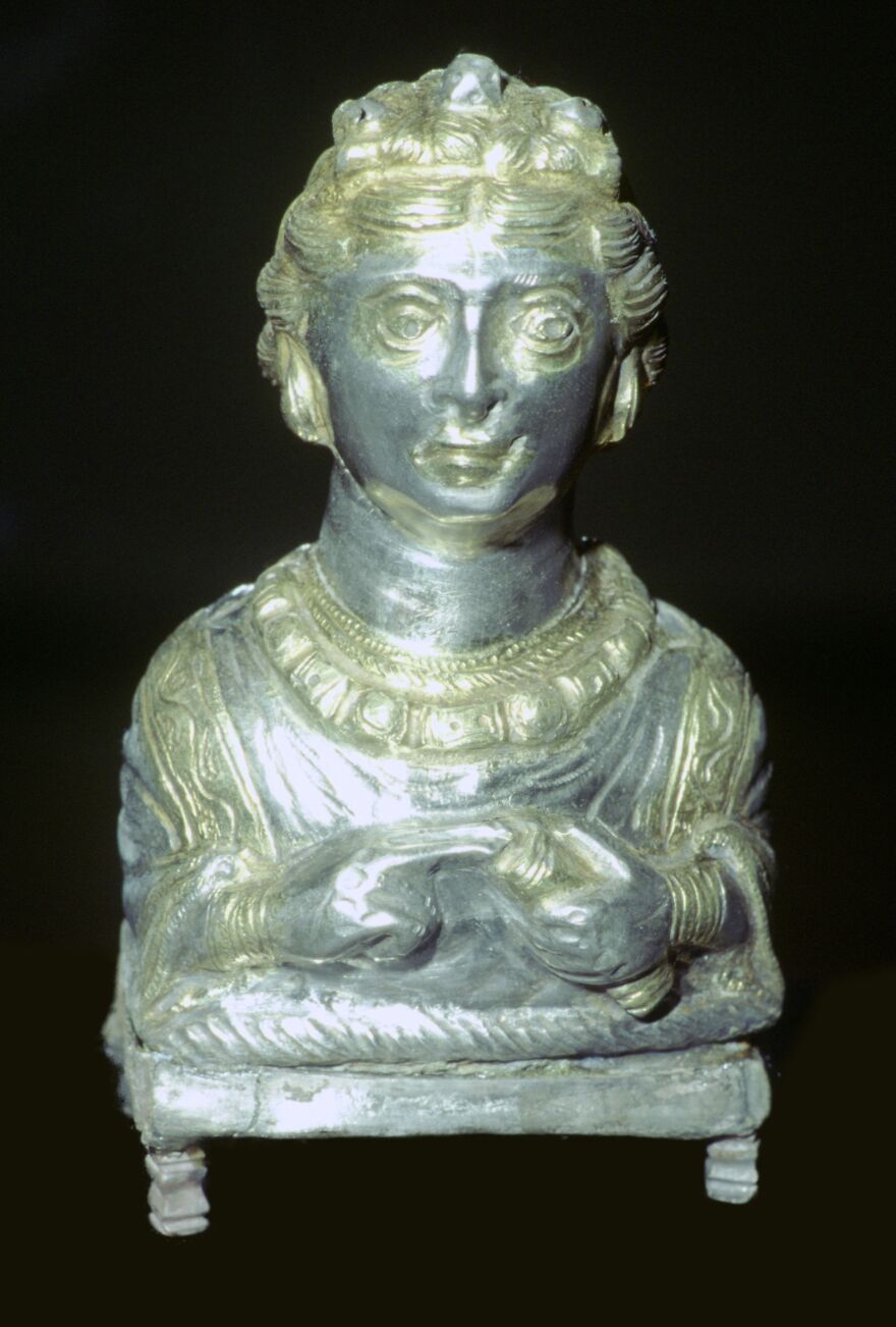 Ancient silver bust of a figure with intricate details and jewelry, a curious object with dazzling origins.