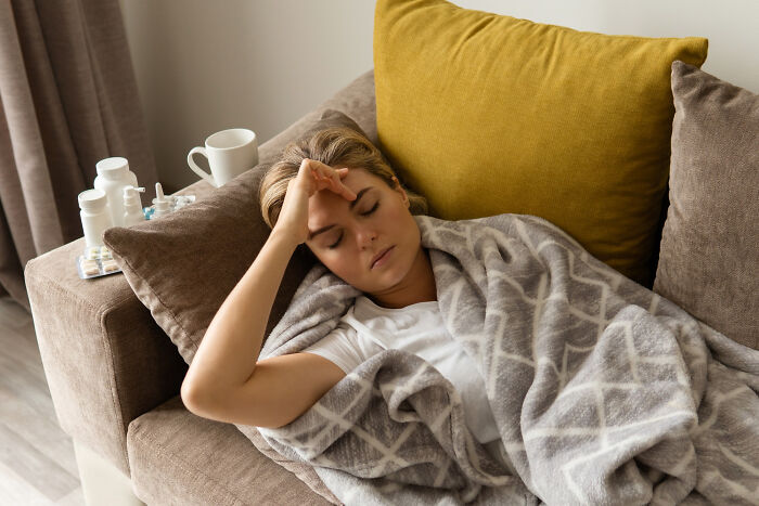 Woman resting on couch with blanket and medication nearby, illustrating things doctors prefer to hide from patients.