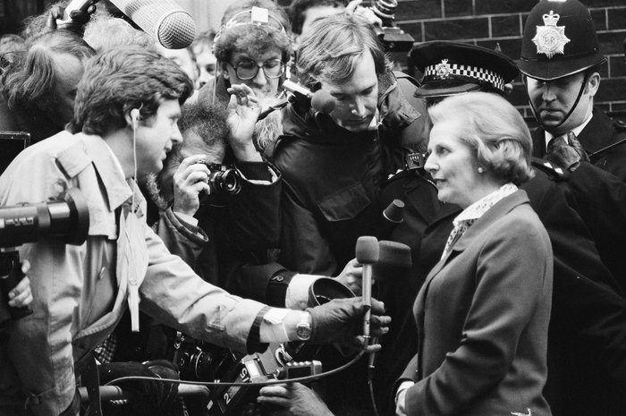 Margaret Thatcher speaking to journalists and police officers during a historic press event, illustrating famous leaders who changed history.