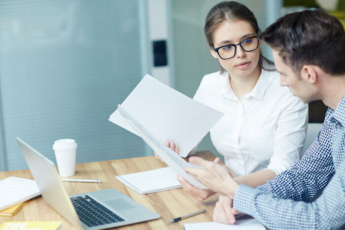 Two coworkers in an office reviewing documents, illustrating karma hitting those who try to sabotage others.