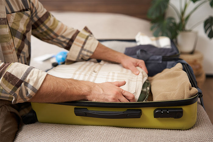 Man packing a suitcase on bed, symbolizing a husband leaving after wife admits to cheating multiple times for variety.