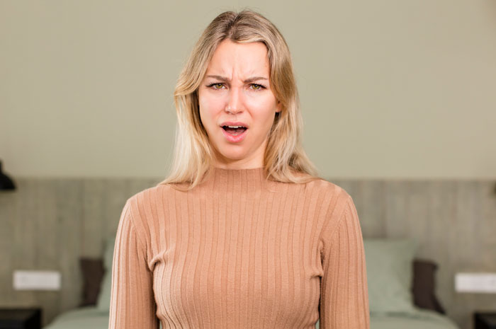 Confused woman in a beige sweater showing regret, illustrating woman trying to coexist with boyfriend&rsquo;s female friend conflict.